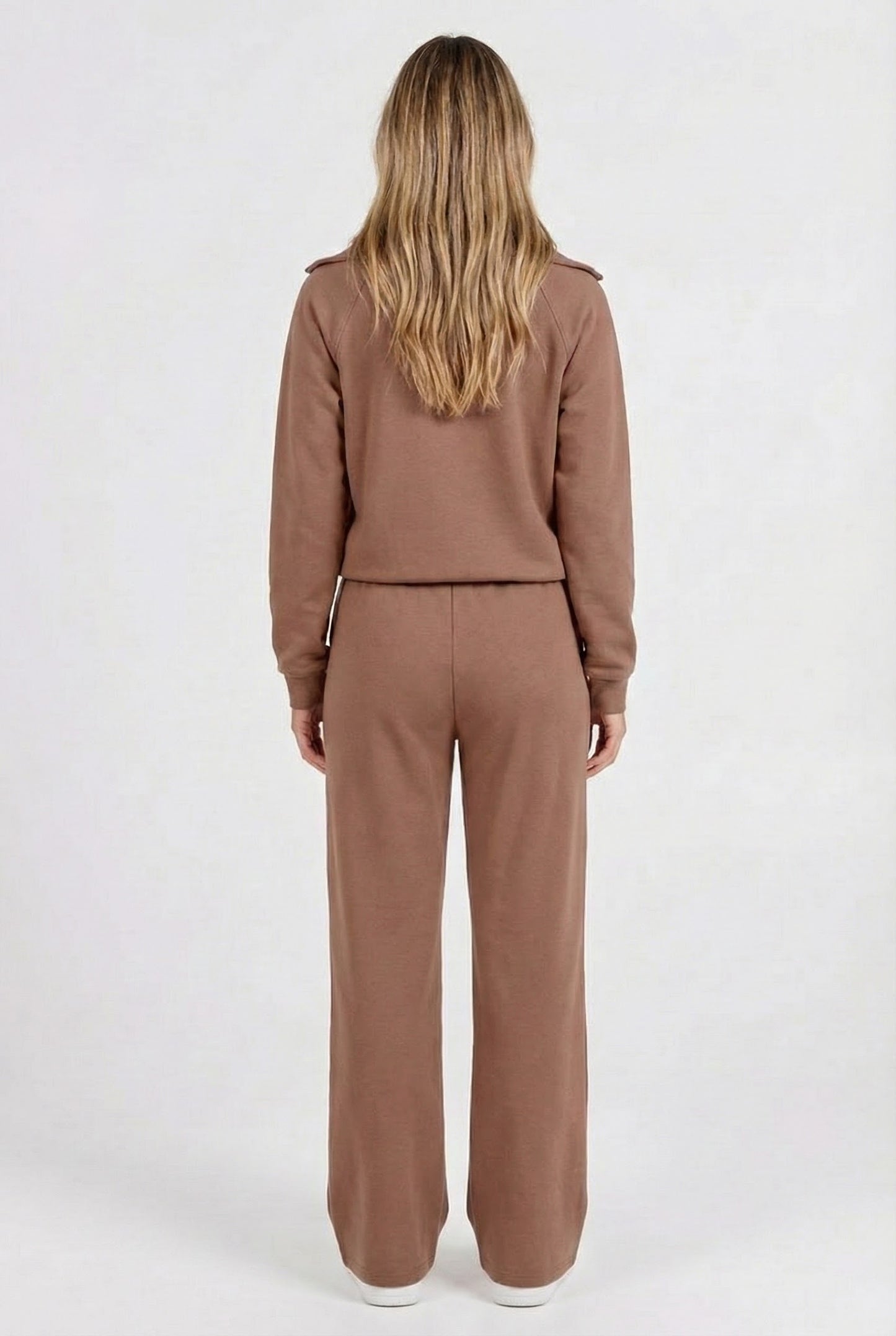 Woman wearing the LOHNR Élan Set in Cocoa Bean, featuring a smooth, sweatshirt-material half-zip pullover and matching structured pants.