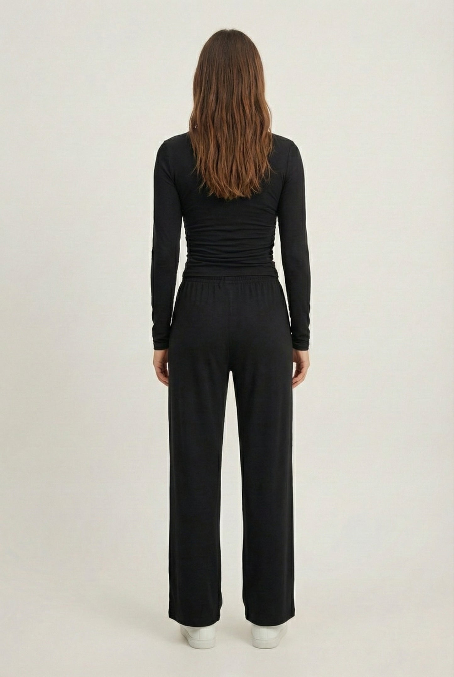 Model wearing The Rive Set sleek stretch lounge set in Noir by Lohnr, featuring a ruched long-sleeve top and wide-leg drawstring pants