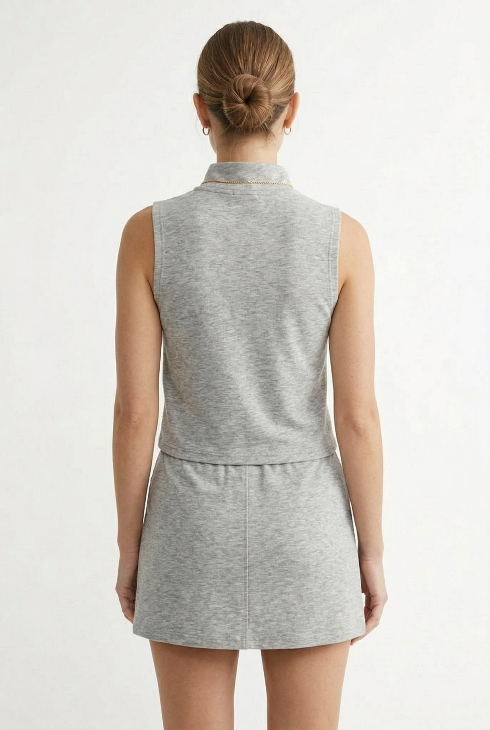 A woman wearing a Heather Light Gray sleeveless athletic dress with a zippered collar and matching skirt.