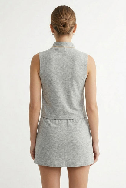 A woman wearing a Heather Light Gray sleeveless athletic dress with a zippered collar and matching skirt.