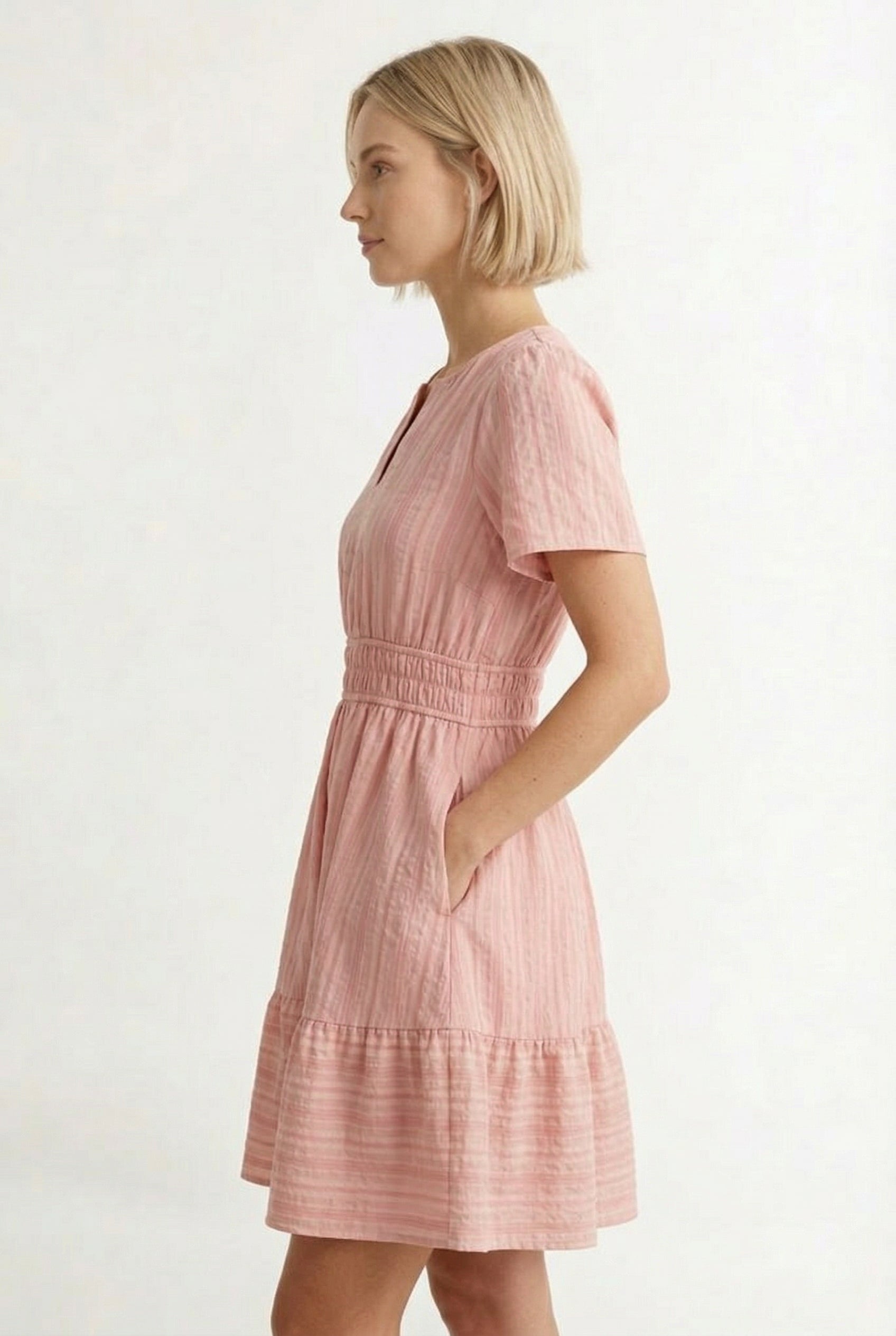 Woman wearing a short sleeve v-neck tiered dress in ash rose pink