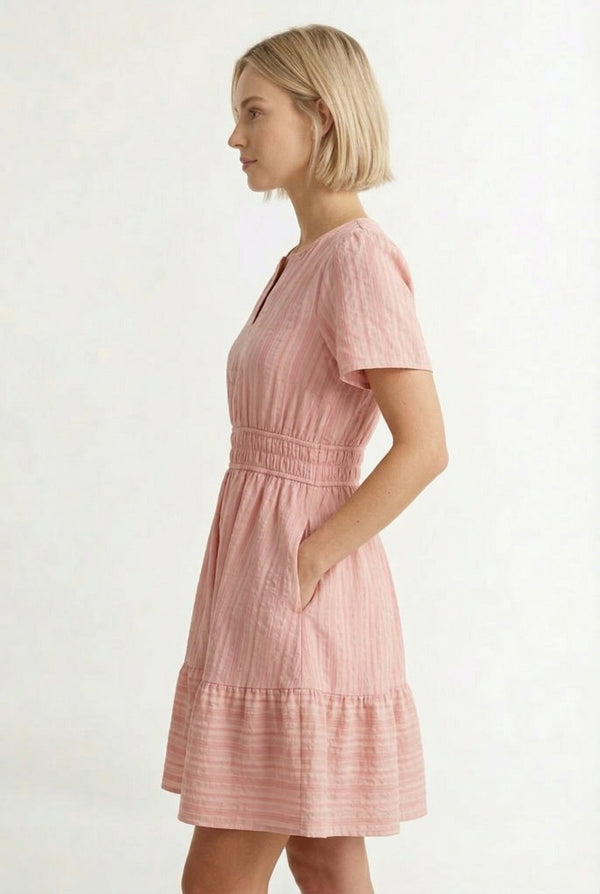 Woman wearing a short sleeve v-neck tiered dress in ash rose pink