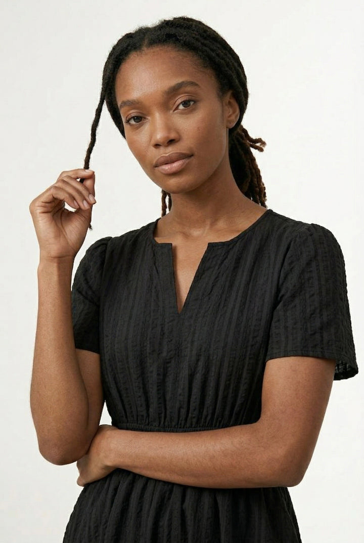 Woman wearing a short sleeve v-neck tiered dress in onyx black