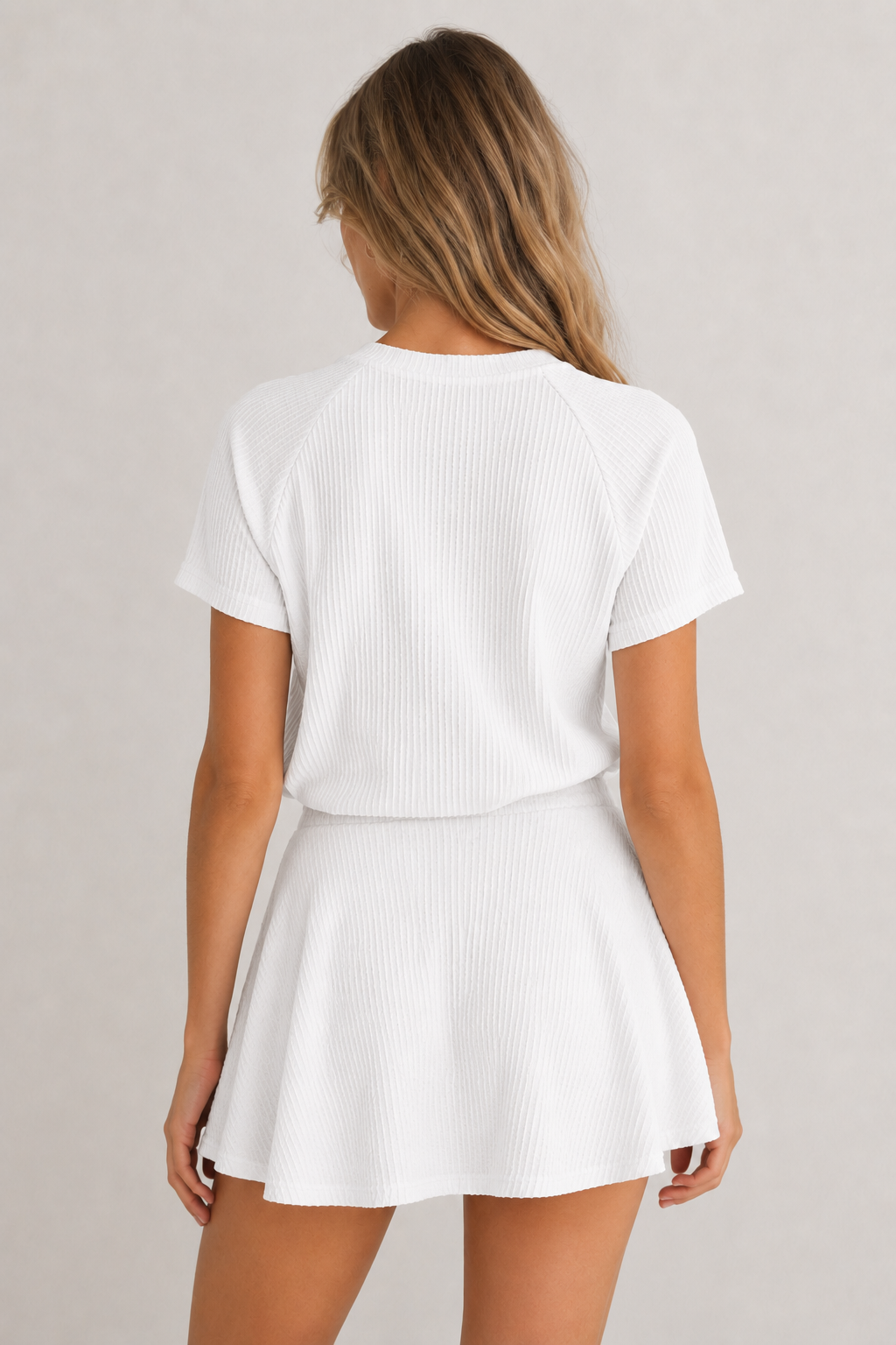 Woman wearing a blanc white short sleeve top and matching mini skirt lounge set.