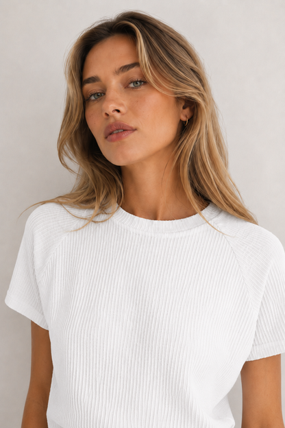 Woman wearing a blanc white short sleeve top and matching mini skirt lounge set.