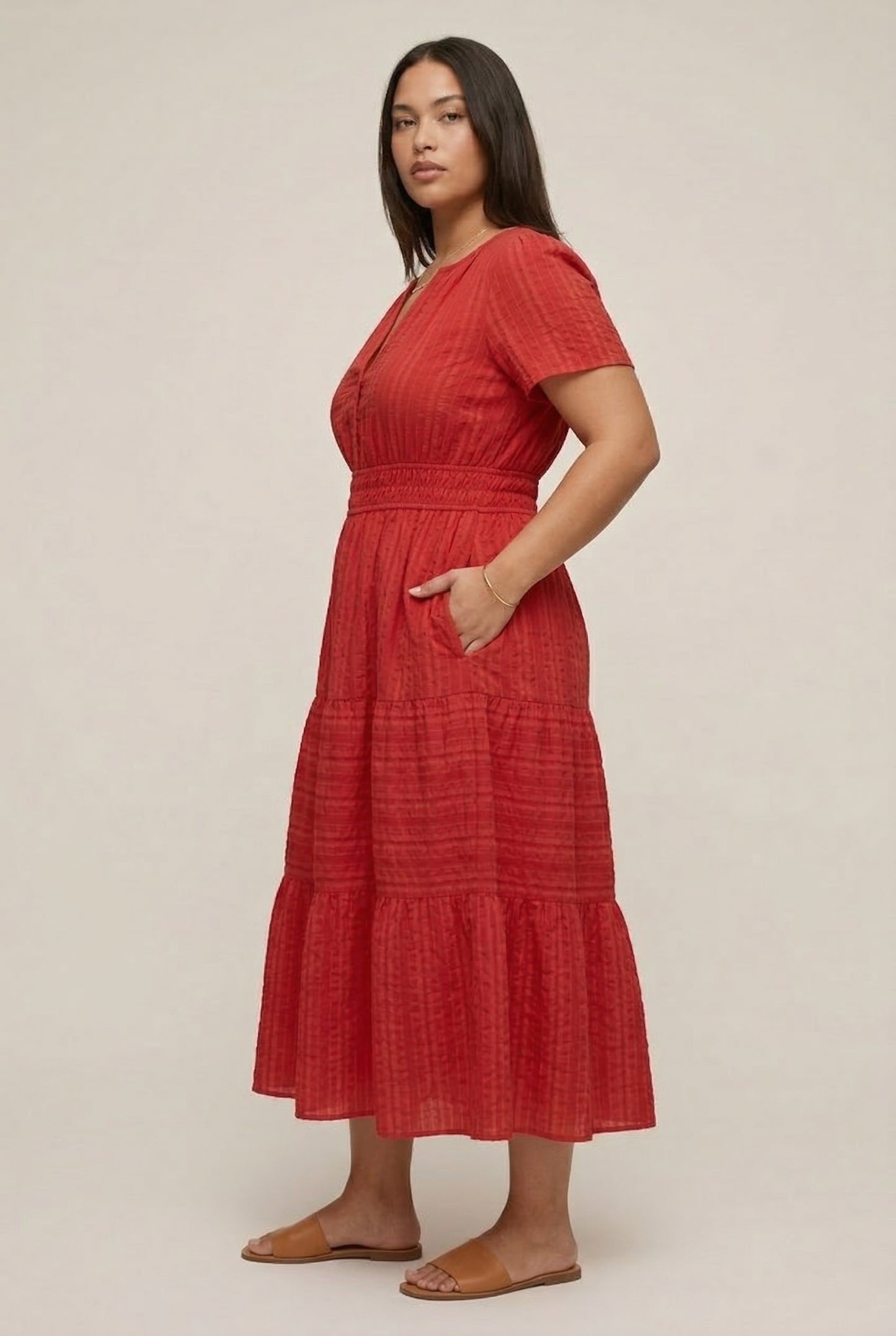 A woman modeling a Cinnabar red short-sleeve midi dress with a button-down front and tiered skirt.