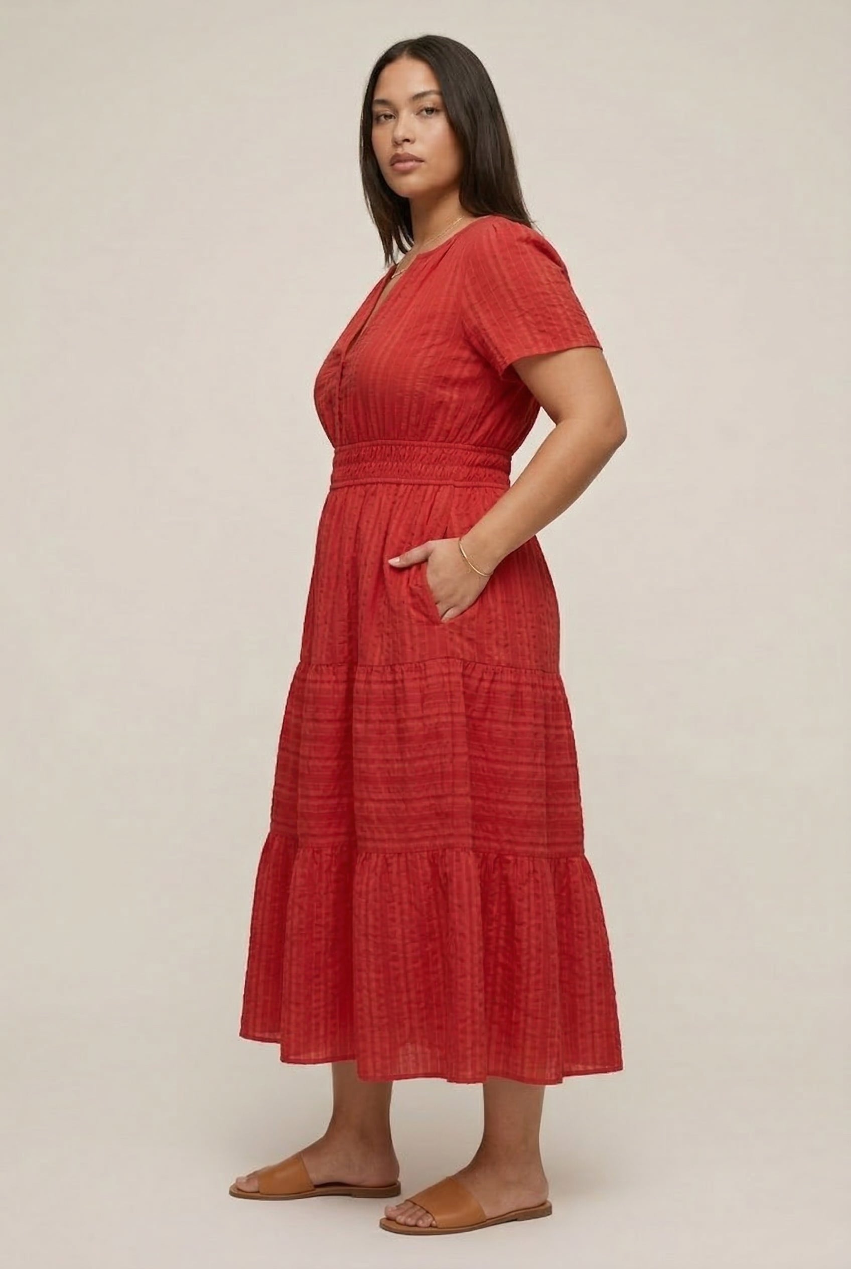 A woman modeling a Cinnabar red short-sleeve midi dress with a button-down front and tiered skirt.