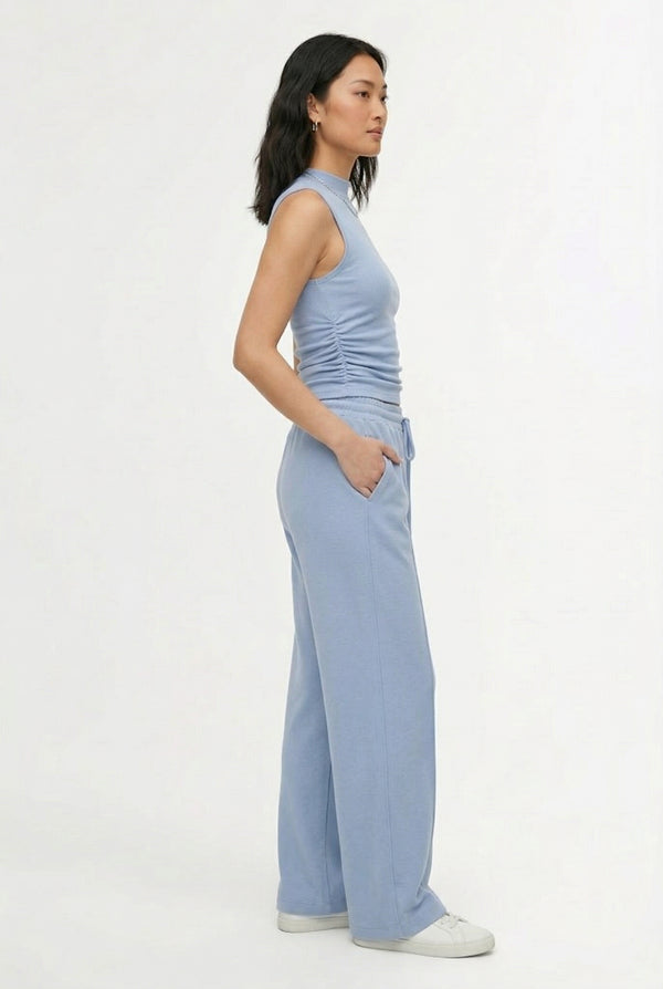 Woman wearing a soft cloud blue sleeveless jumpsuit featuring wide-cut legs.