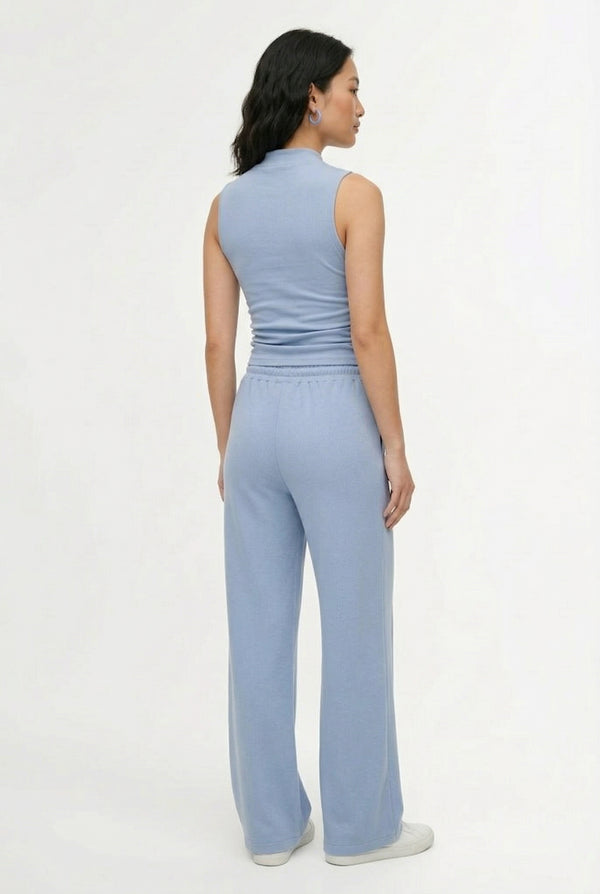 Woman wearing a soft cloud blue sleeveless jumpsuit featuring wide-cut legs.