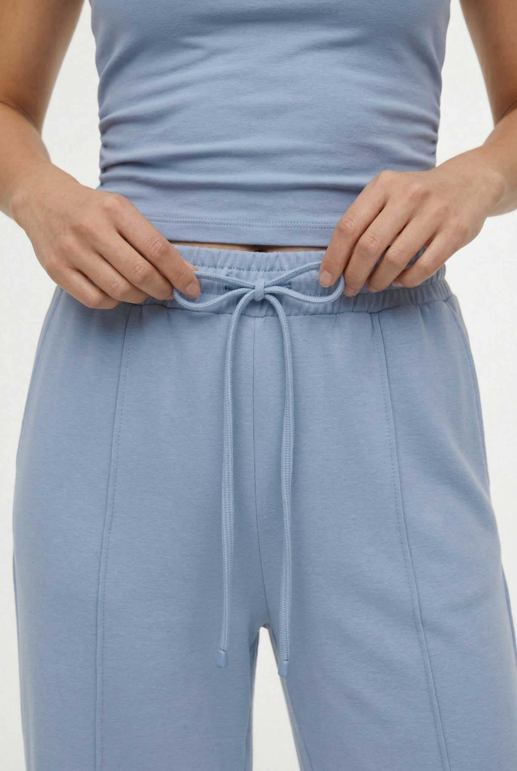 Woman wearing a soft cloud blue sleeveless jumpsuit featuring wide-cut legs.