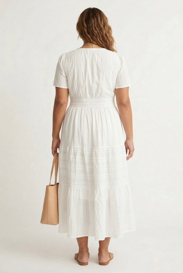A woman wearing a Cloud White short-sleeve midi dress with a button-down front and tiered skirt.