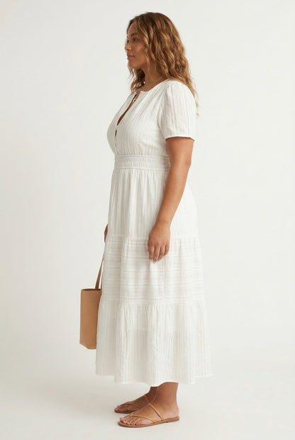 A woman wearing a Cloud White short-sleeve midi dress with a button-down front and tiered skirt.