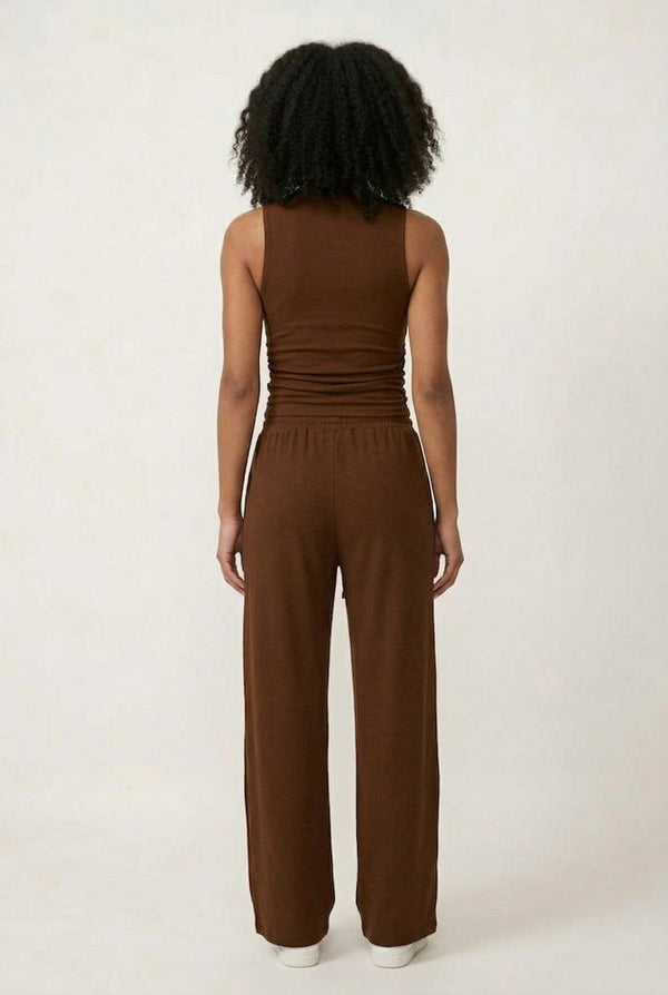 Woman wearing a warm cognac brown sleeveless jumpsuit with wide legs.