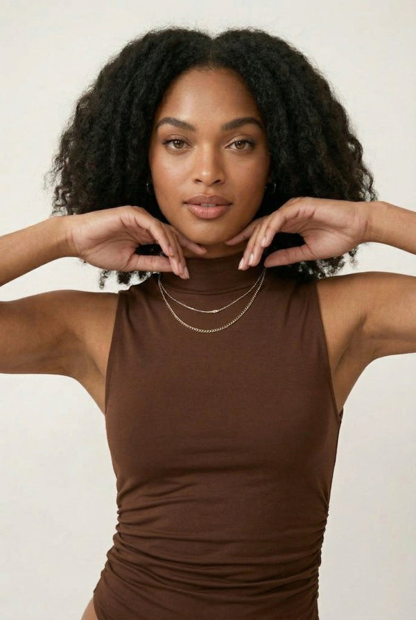 Woman wearing a warm cognac brown sleeveless jumpsuit with wide legs.