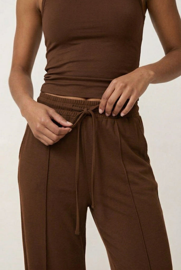 Woman wearing a warm cognac brown sleeveless jumpsuit with wide legs.