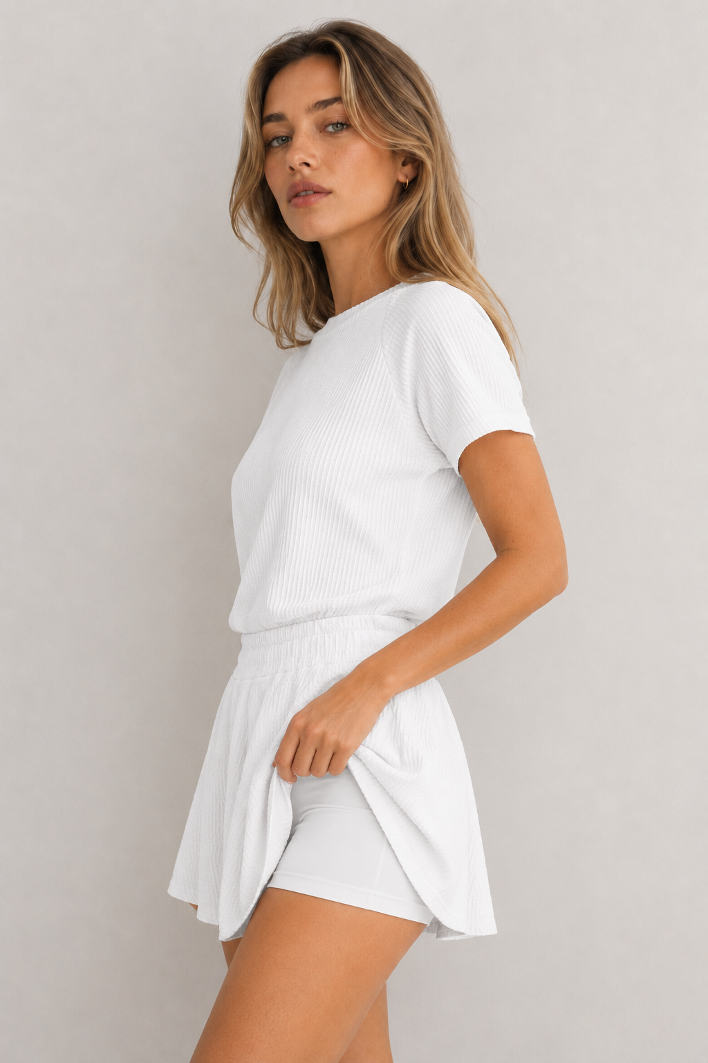 Woman wearing a blanc white short sleeve top and matching mini skirt lounge set.