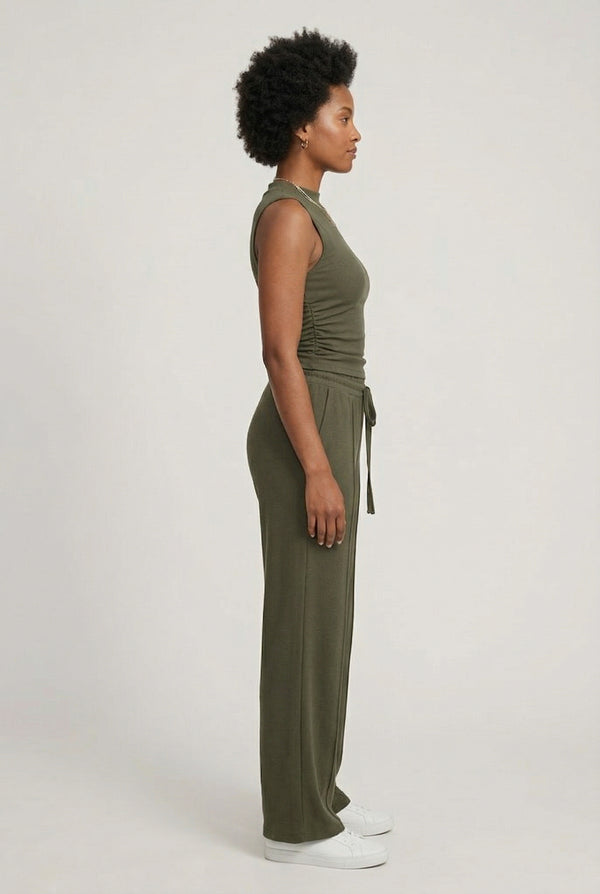Woman wearing a dark olive green sleeveless jumpsuit with wide legs.