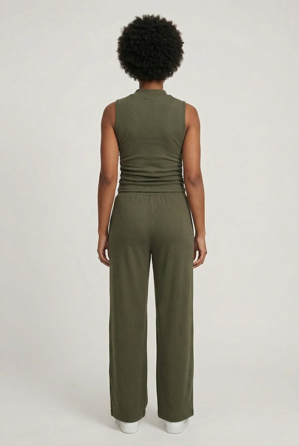 Woman wearing a dark olive green sleeveless jumpsuit with wide legs.