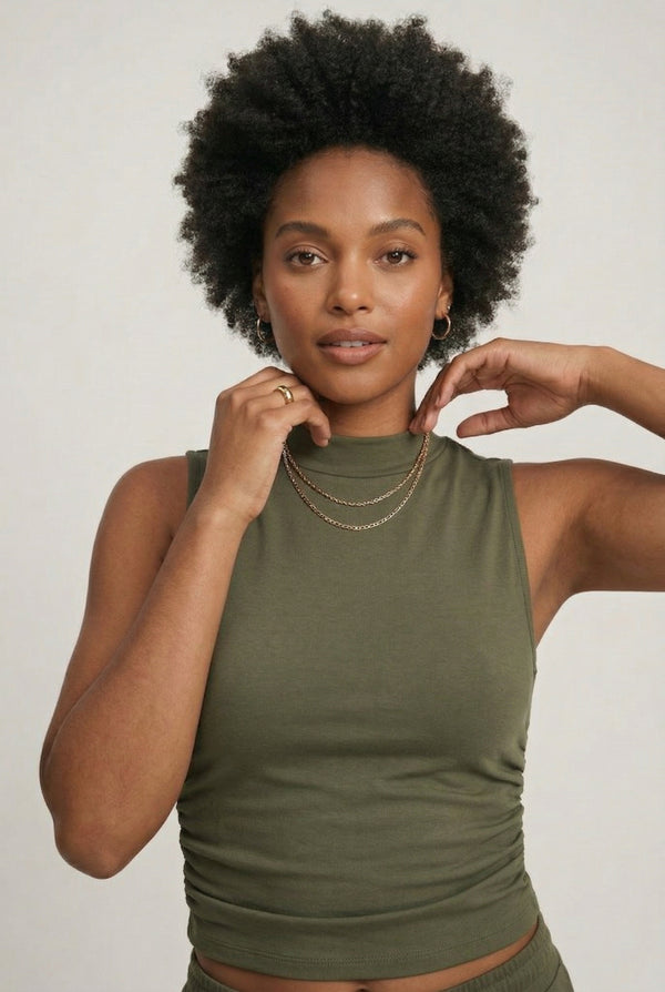 Woman wearing a dark olive green sleeveless jumpsuit with wide legs.