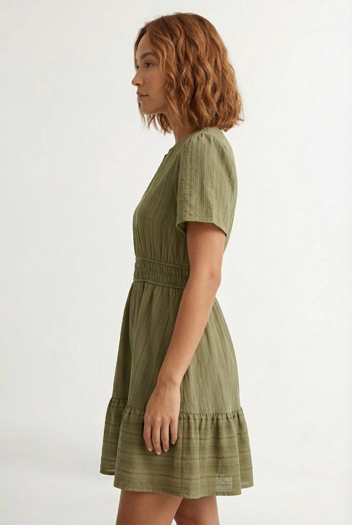 Woman wearing a short sleeve v-neck tiered dress in dark olive green