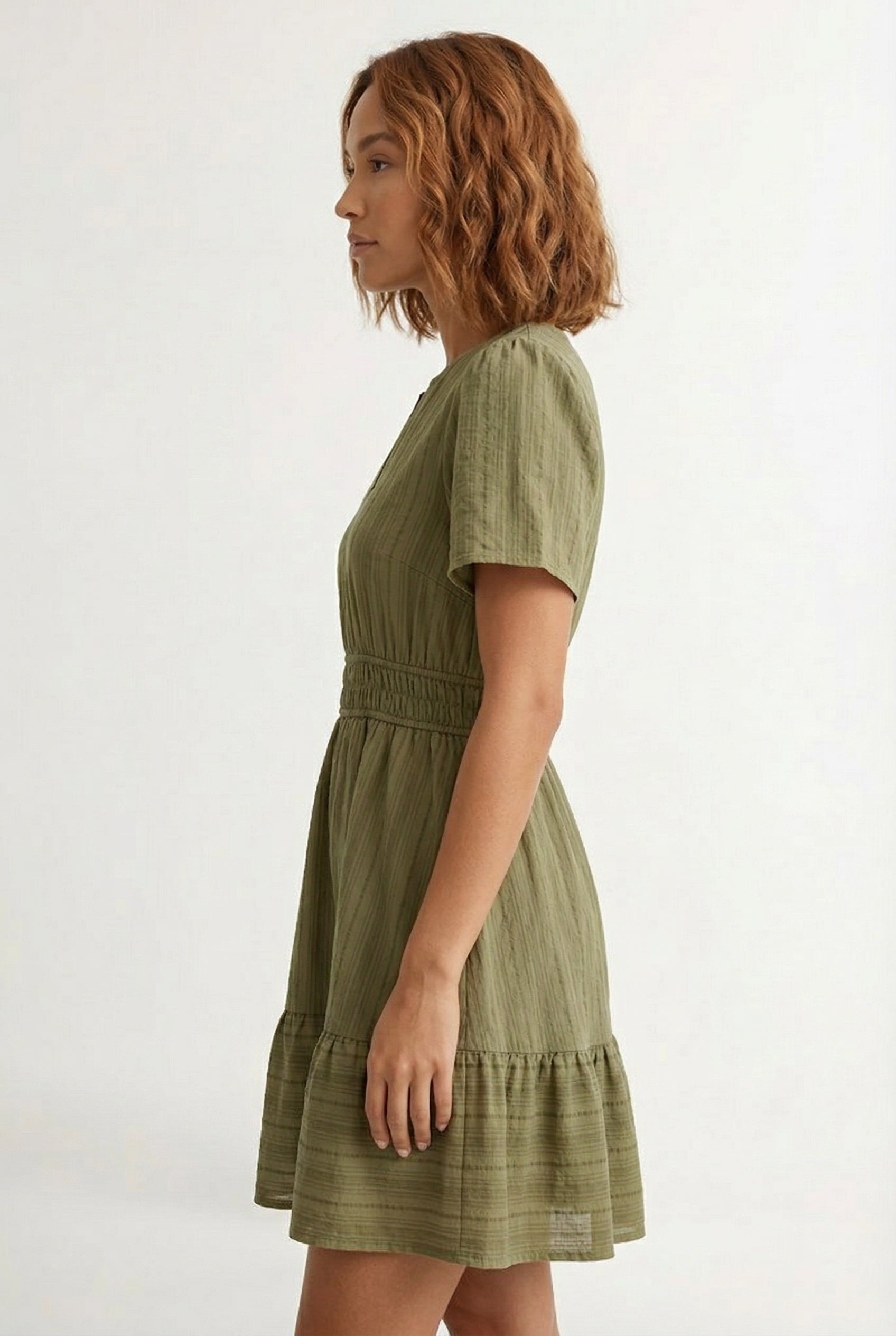 Woman wearing a short sleeve v-neck tiered dress in dark olive green