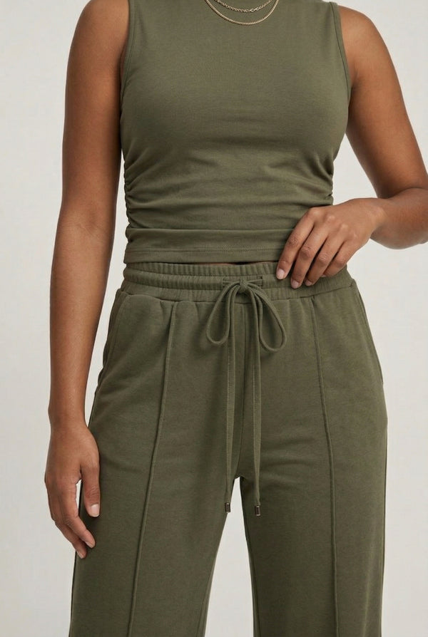 Woman wearing a dark olive green sleeveless jumpsuit with wide legs.