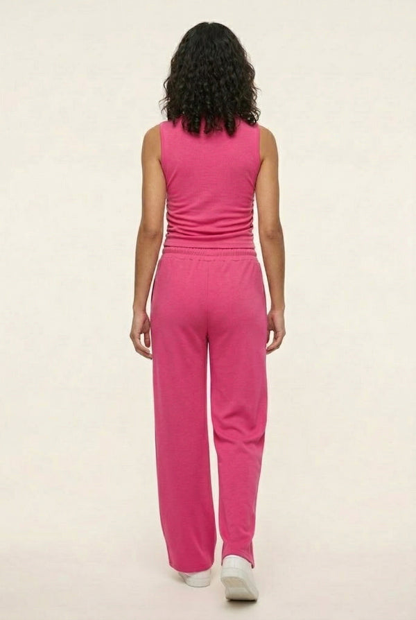 Woman wearing a vibrant dragonfruit pink sleeveless jumpsuit with a wide-leg fit.