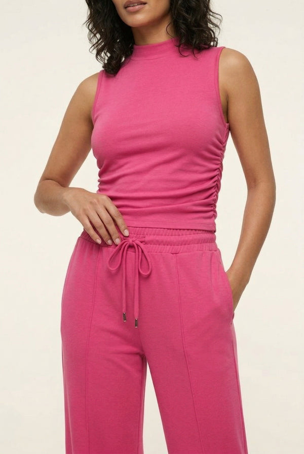 Woman wearing a vibrant dragonfruit pink sleeveless jumpsuit with a wide-leg fit.