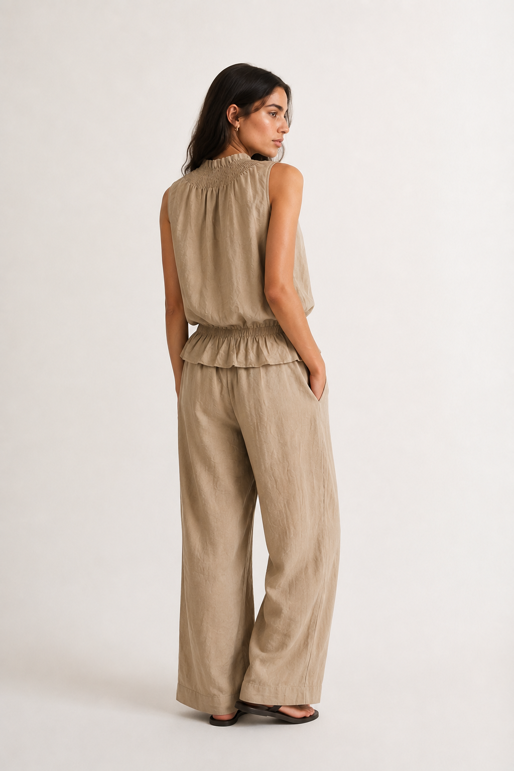 Woman wearing a premium minimalist dune beige two piece set with sleeveless top and wide leg pants
