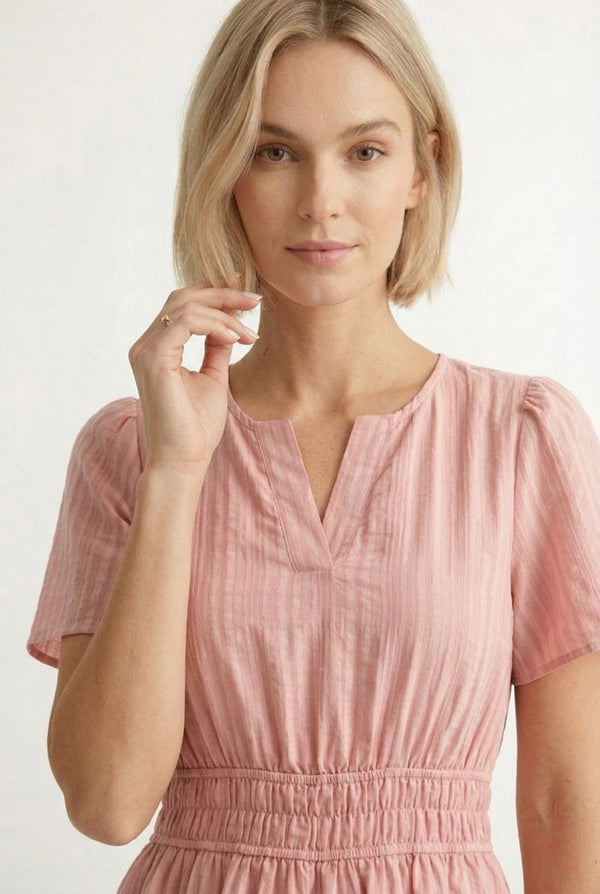 Woman wearing a short sleeve v-neck tiered dress in ash rose pink