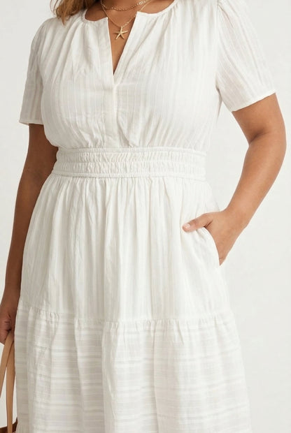 A woman wearing a Cloud White short-sleeve midi dress with a button-down front and tiered skirt.