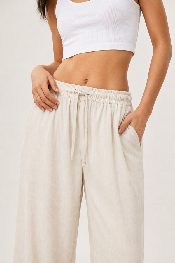 Woman modeling premium high-waisted wide-leg pants in off-white Ecru against a clean studio background