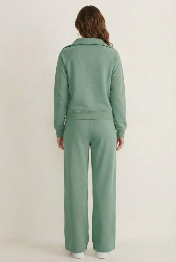 Woman wearing the LOHNR Élan Set in Eucalyptus, featuring a smooth, sweatshirt-material half-zip pullover and matching structured pants.