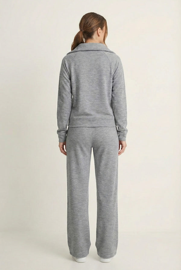 Woman wearing the LOHNR Élan Set in Heather Fog, featuring a smooth, sweatshirt-material half-zip pullover and matching structured pants.