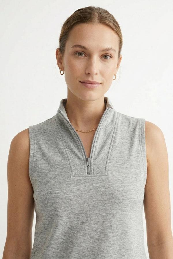 A woman wearing a Heather Light Gray sleeveless athletic dress with a zippered collar and matching skirt.