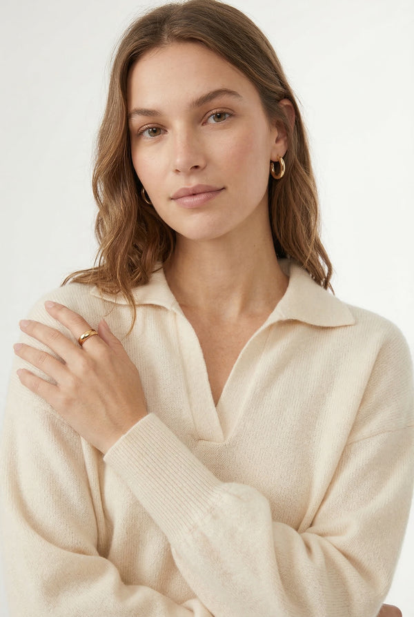 Woman wearing the LOHNR Amélie Collared Sweater in light birch, featuring a relaxed V-neck and structured polo collar.