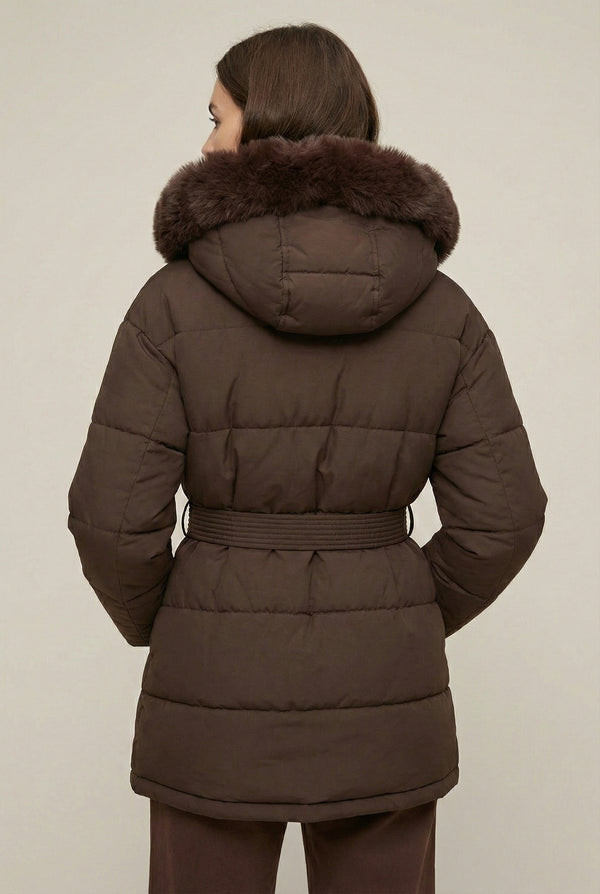Woman modeling the belted Aspen puffer jacket in Mocha by LOHNR, featuring a detachable faux fur hood.