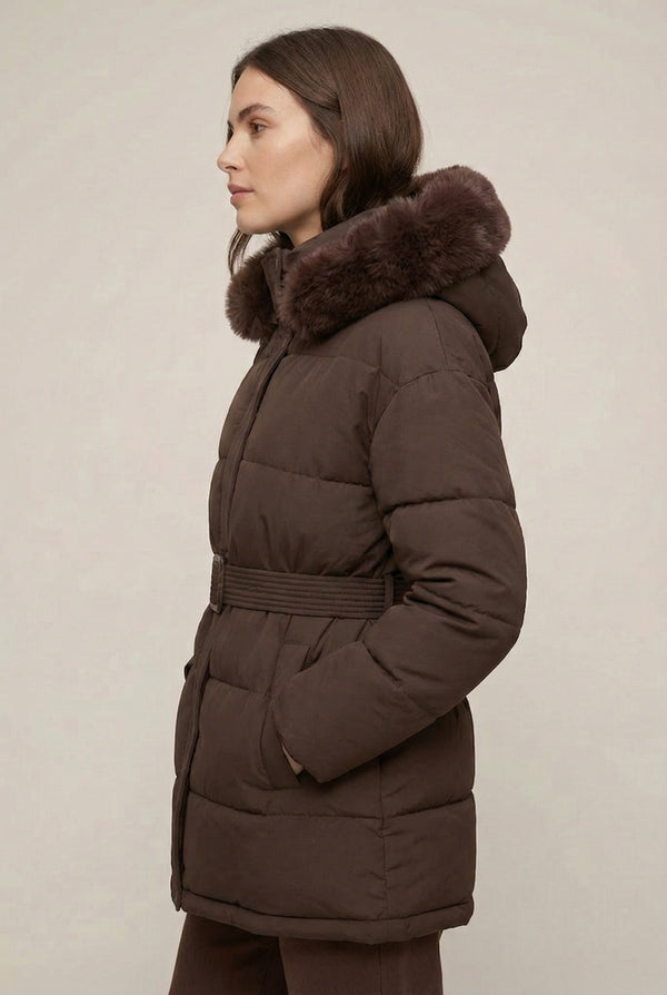 Woman modeling the belted Aspen puffer jacket in Mocha by LOHNR, featuring a detachable faux fur hood.