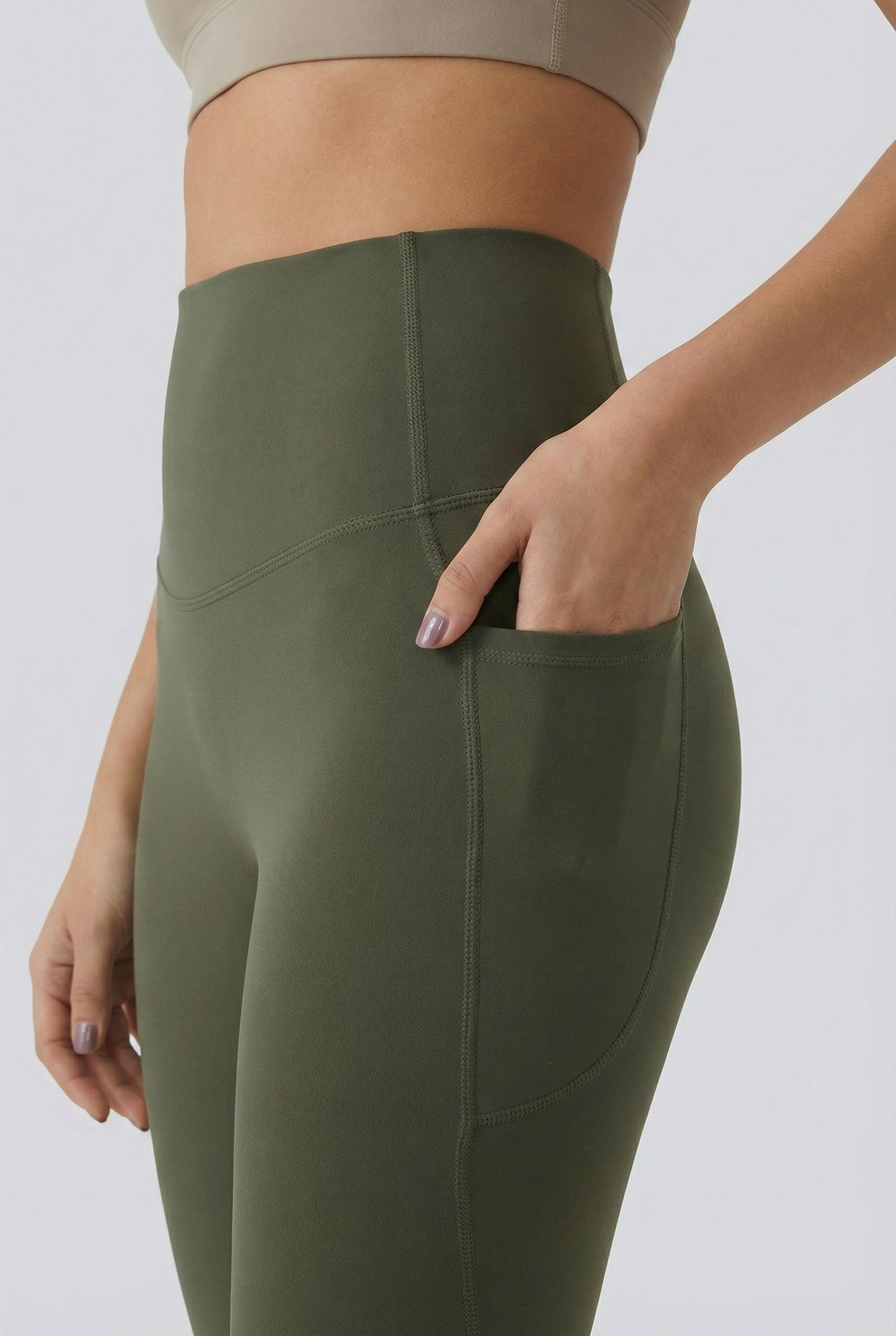 Women's high-waisted Contour Pocket Legging in Alpine green, featuring a seamless front, hidden side pockets, and body-contouring compression fit.