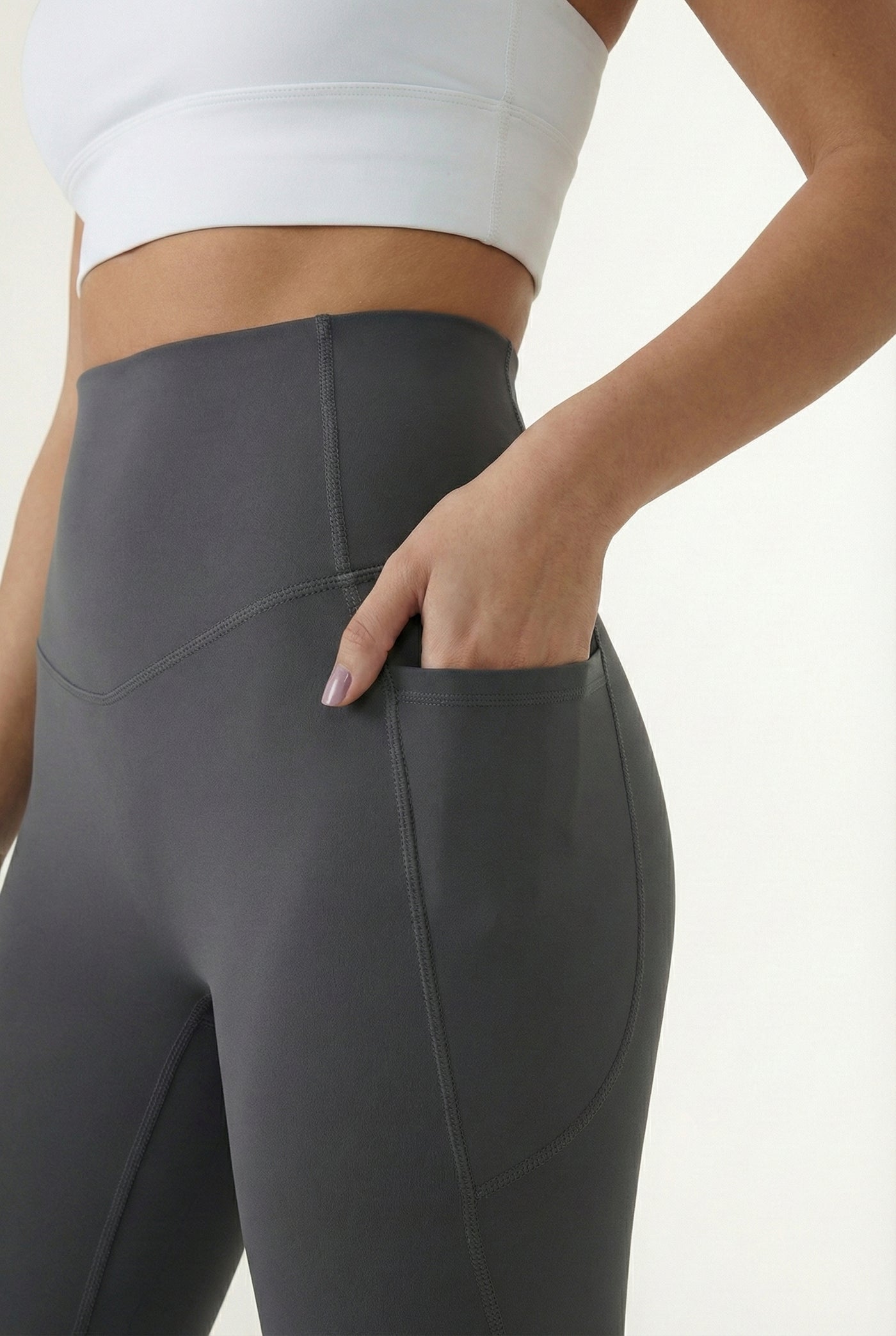 Women's high-waisted Contour Pocket Legging in Asphalt grey, featuring a seamless front, hidden side pockets, and body-contouring compression fit.