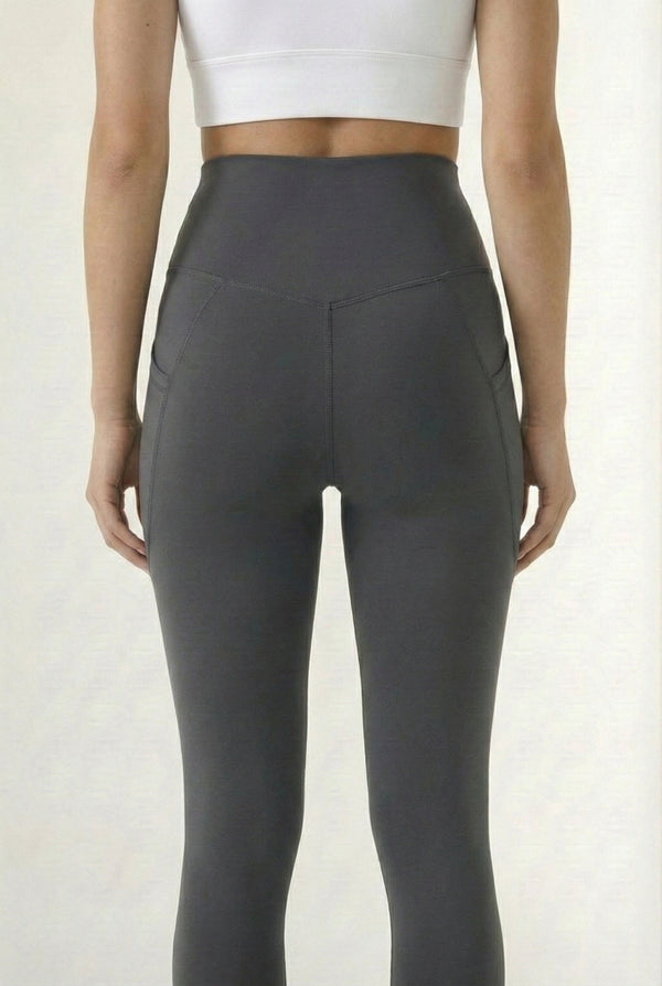 Women's high-waisted Contour Pocket Legging in Asphalt grey, featuring a seamless front, hidden side pockets, and body-contouring compression fit.