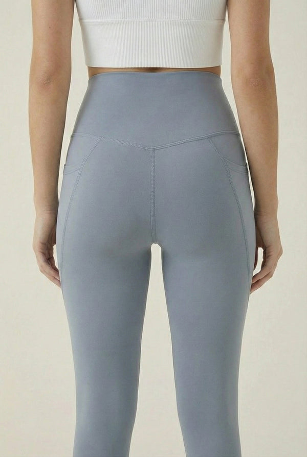 Women's high-waisted Contour Pocket Legging in Chambray blue, featuring a seamless front, hidden side pockets, and body-contouring compression fit.
