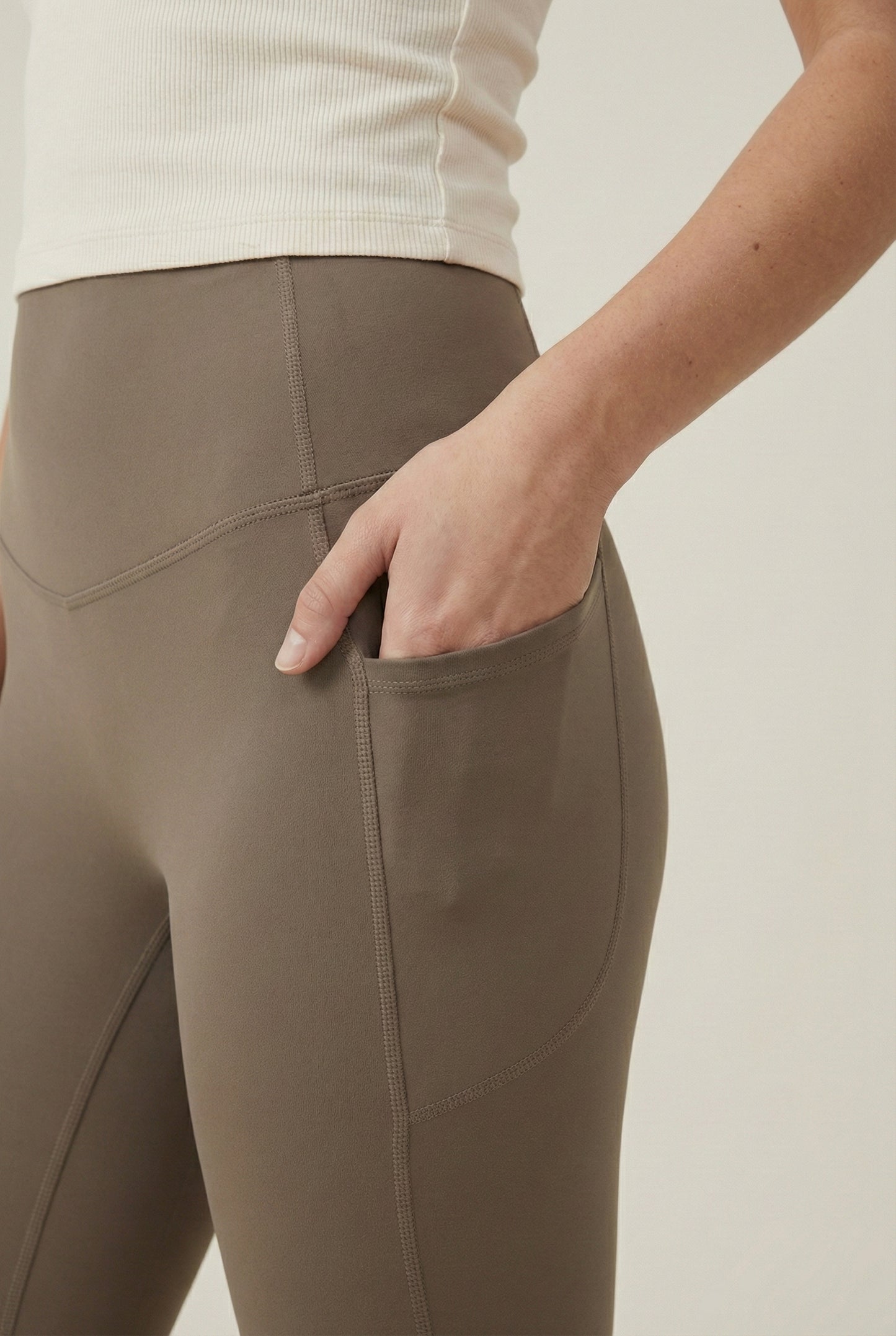 Women's high-waisted Contour Pocket Legging in Portabella brown, featuring a seamless front, hidden side pockets, and body-contouring compression fit.