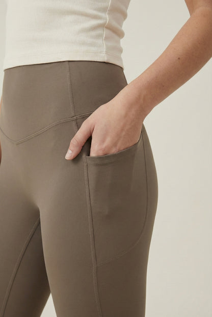 Women's high-waisted Contour Pocket Legging in Portabella brown, featuring a seamless front, hidden side pockets, and body-contouring compression fit.