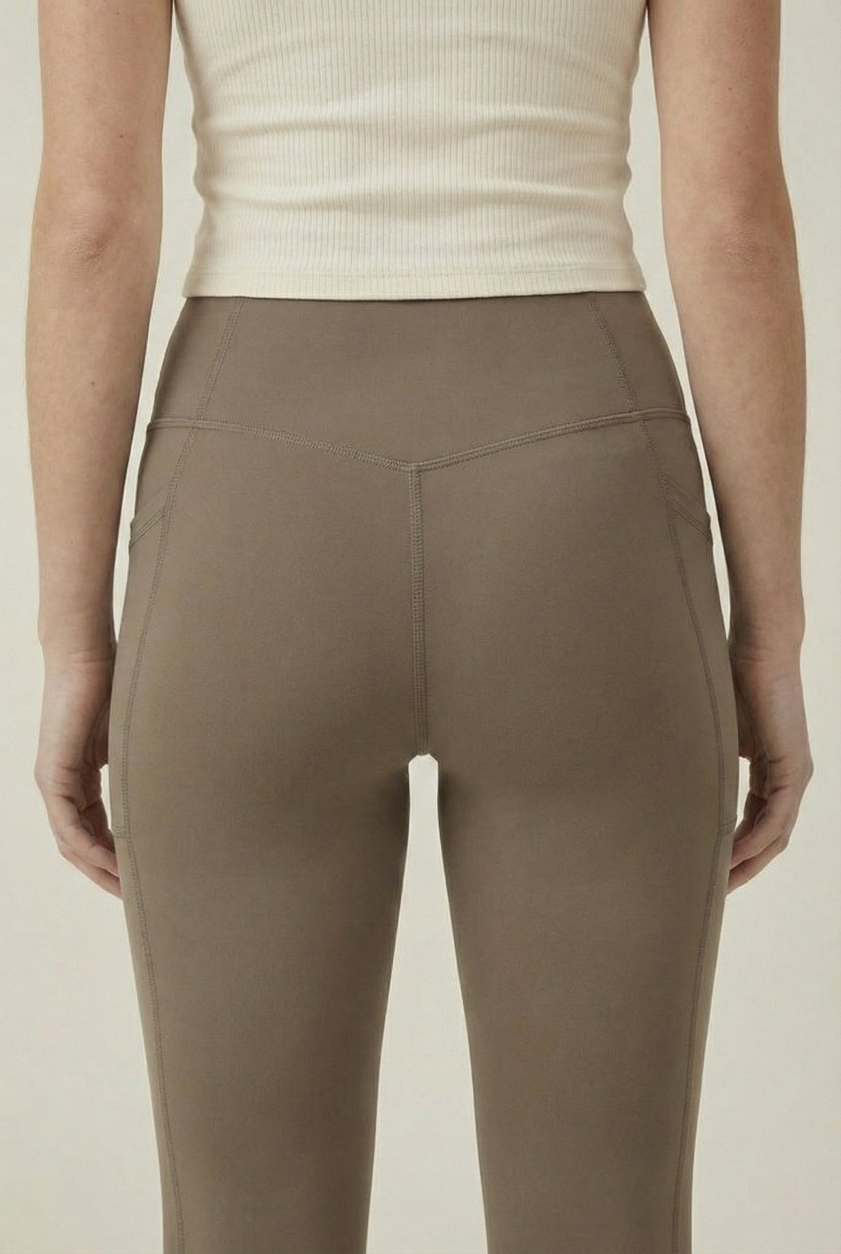 Women's high-waisted Contour Pocket Legging in Portabella brown, featuring a seamless front, hidden side pockets, and body-contouring compression fit.