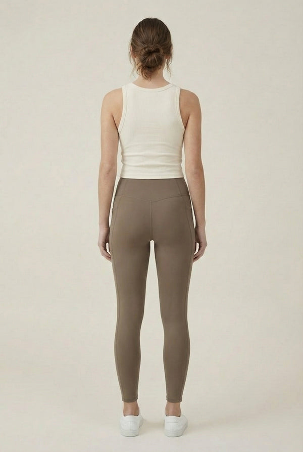 Women's high-waisted Contour Pocket Legging in Portabella brown, featuring a seamless front, hidden side pockets, and body-contouring compression fit.