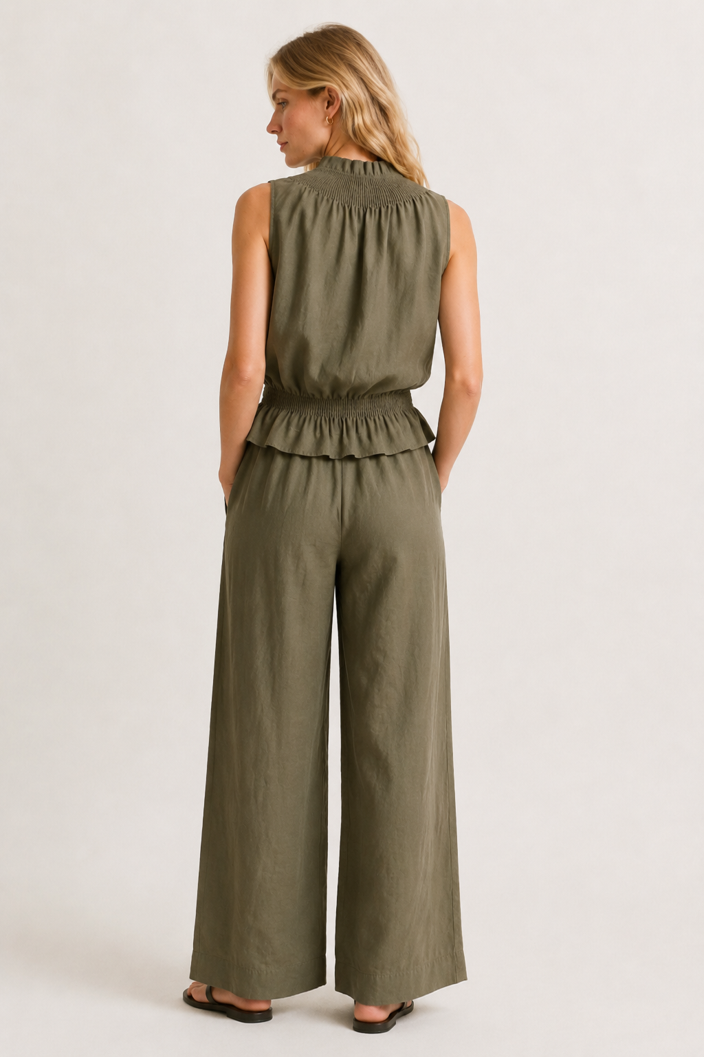 Woman wearing a premium minimalist cypress green two piece set with sleeveless top and wide leg pants