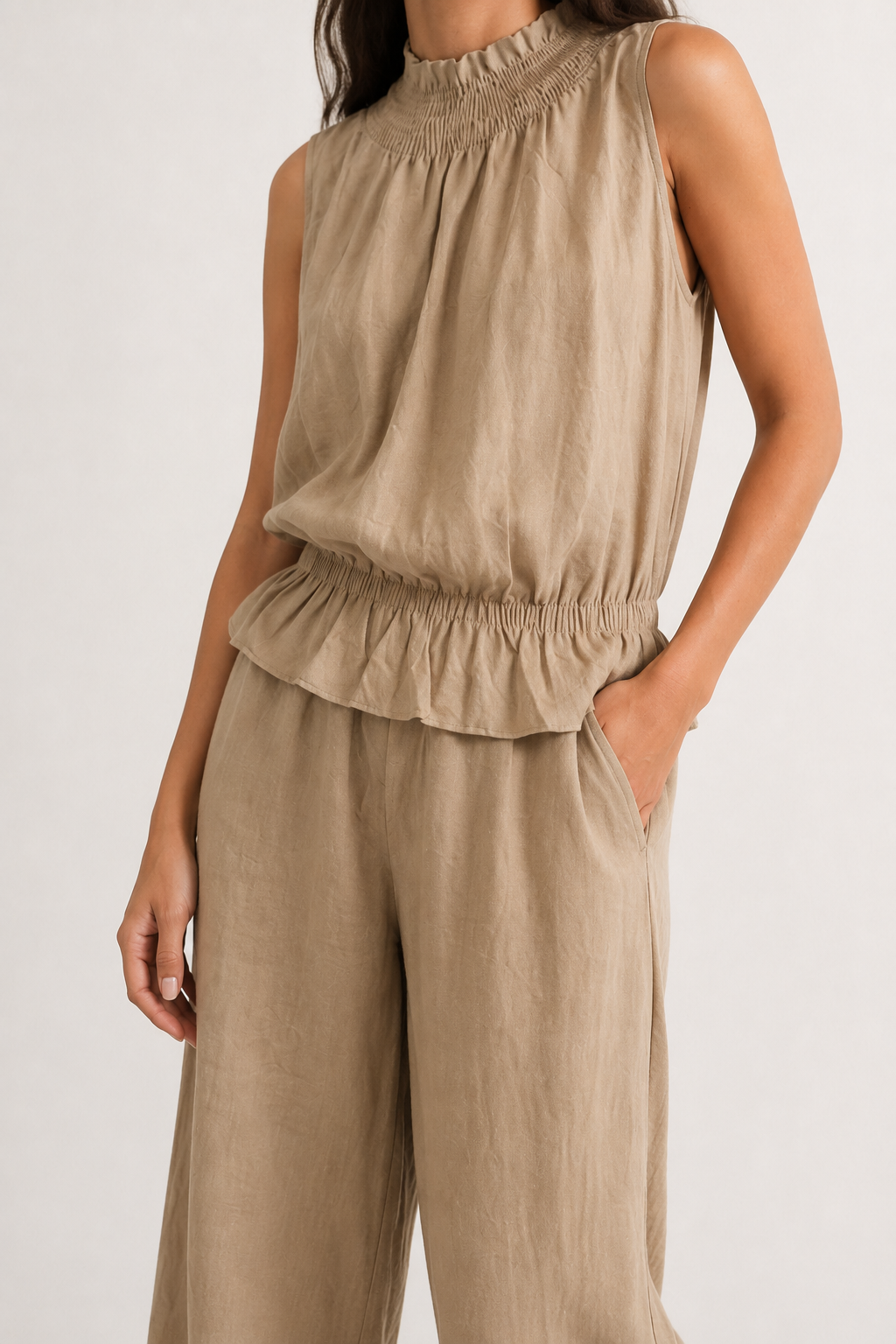 Woman wearing a premium minimalist dune beige two piece set with sleeveless top and wide leg pants