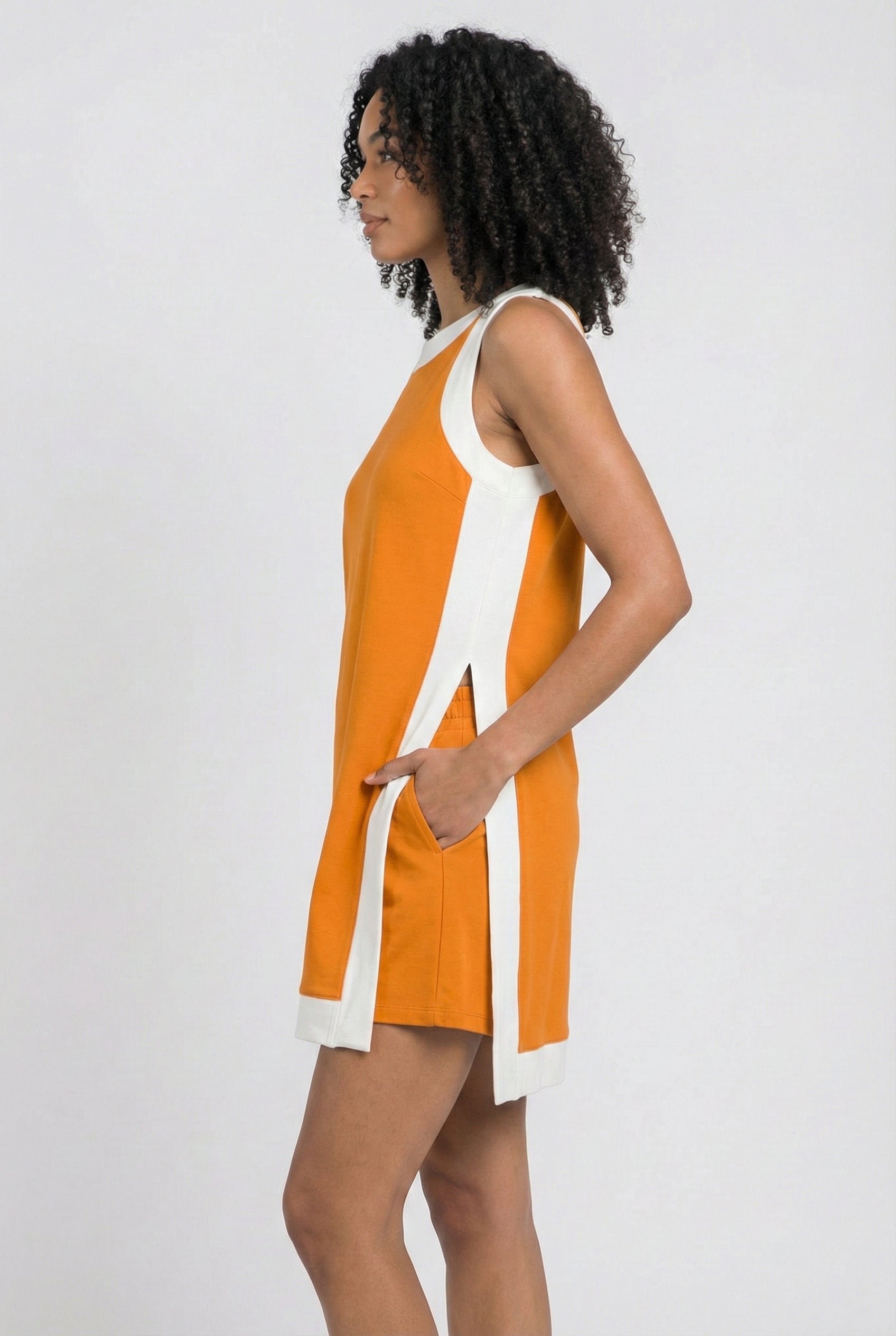 Model wearing the Lohnr Game Day Set in Bright Orange, a 100% cotton two-piece outfit featuring hidden shorts with pockets.