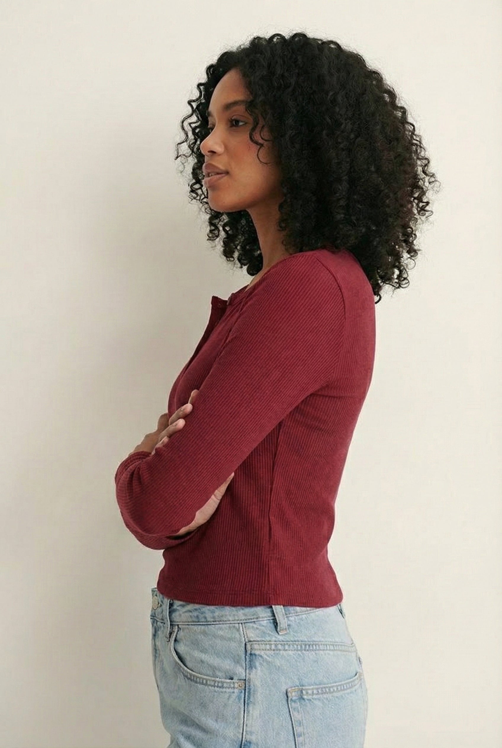 Woman wearing the LOHNR Haven Henley in Cabernet, a deep burgundy ribbed long-sleeve top with a button placket, styled for effortless everyday luxury.